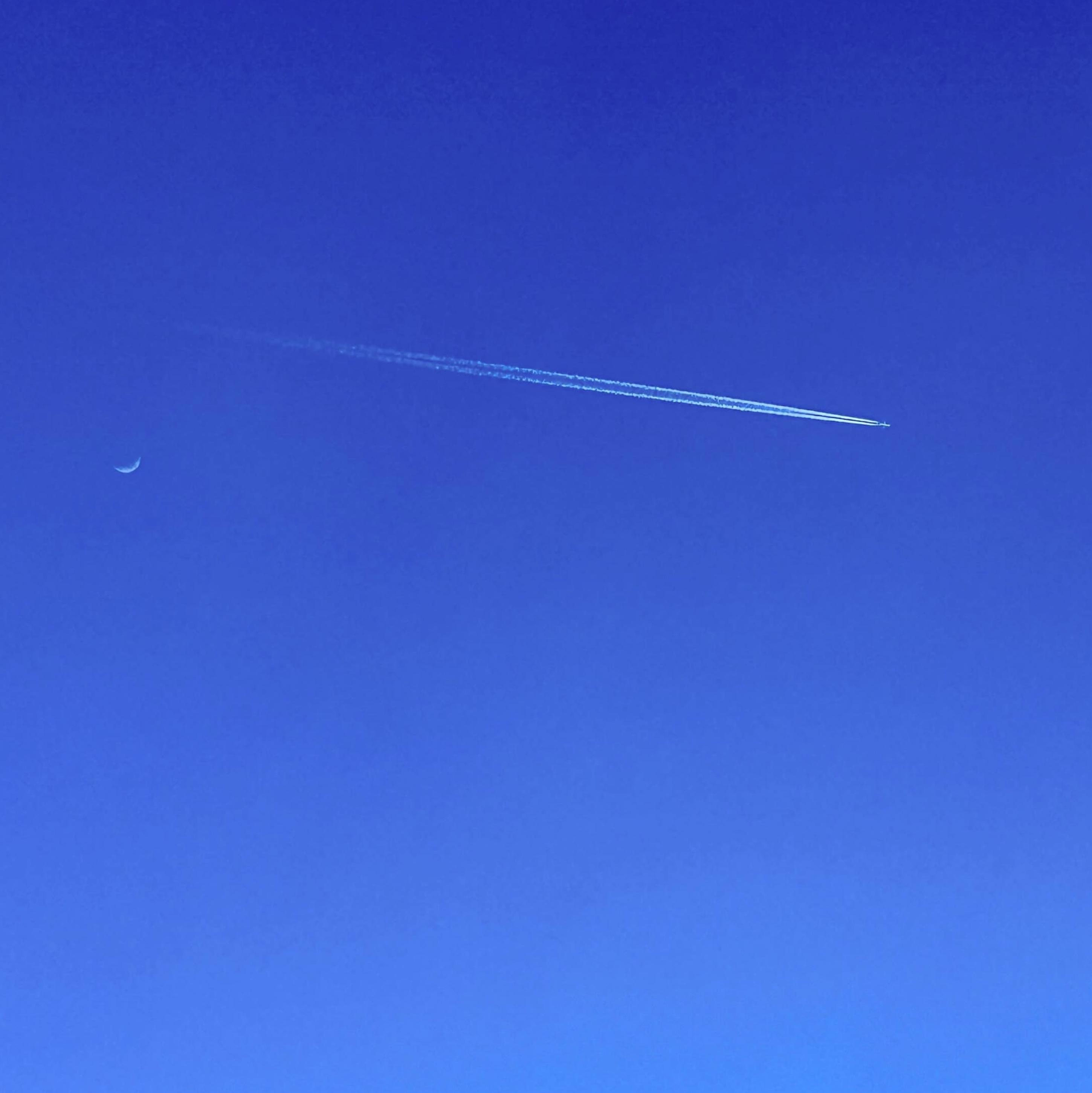 A plane in the sky and the moon