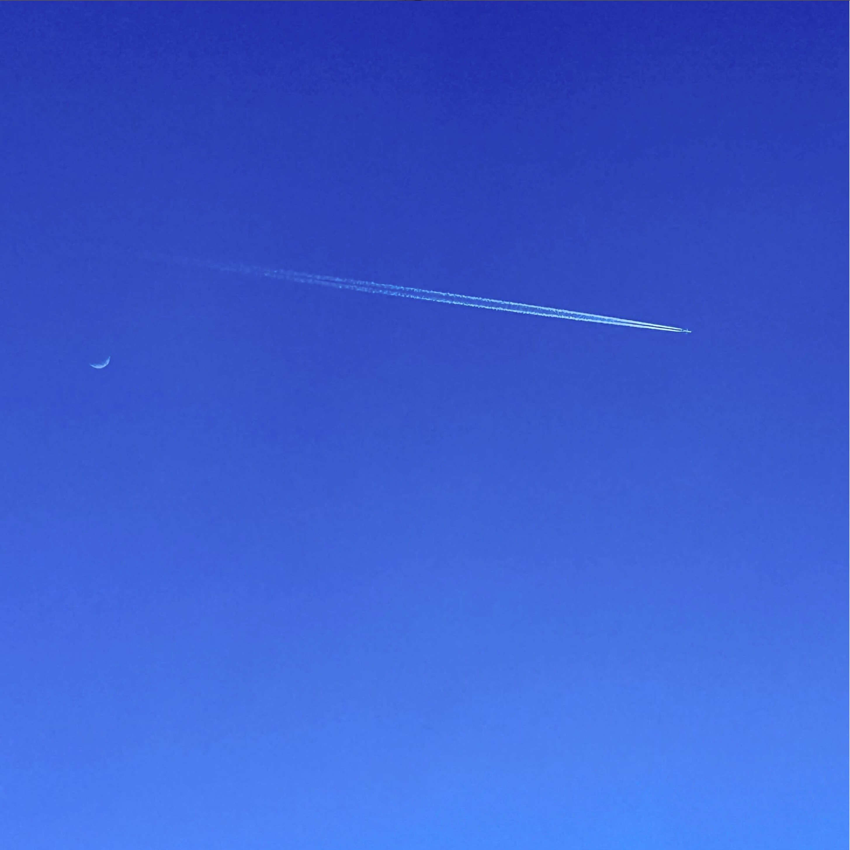 A plane in the sky and the moon
